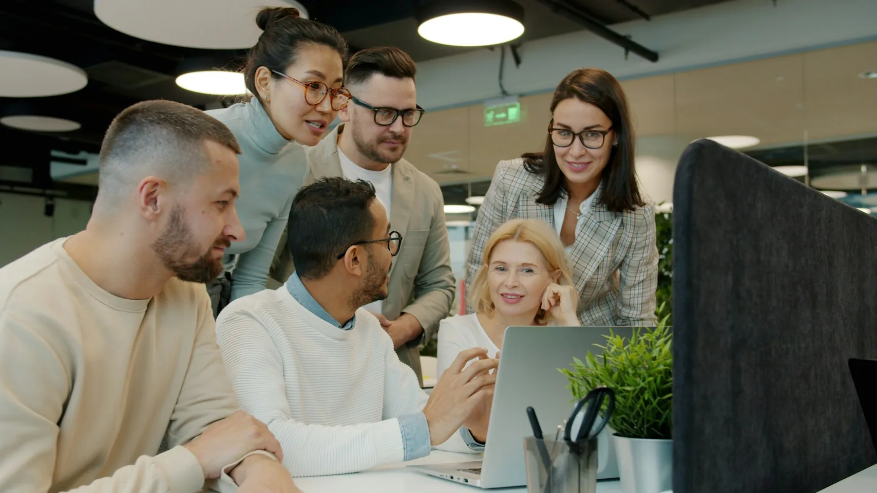 Marketing agency team collaborating around a laptop